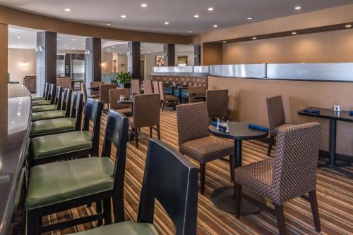 a restaurant with tables and chairs and a bar at Holiday Inn Ontario Airport - California by IHG in Ontario