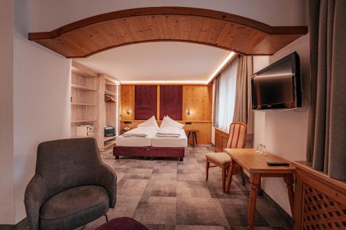 a hotel room with a bed and a chair at Hotel Grieshof in Sankt Anton am Arlberg