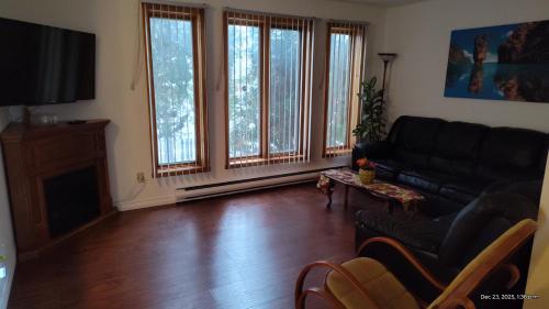 a living room with a black couch and some windows at Family-Friendly in Quiet Laval Neighborhood in Laval