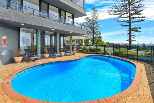 a large blue swimming pool in front of a building at ibis Styles Port Macquarie in Port Macquarie