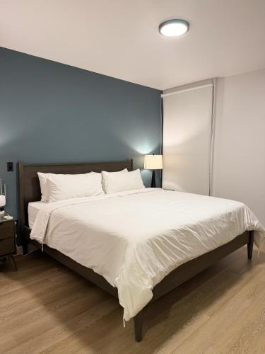 a bedroom with a large white bed with a blue wall at Castillo Toscana Hotel Boutique in Ensenada