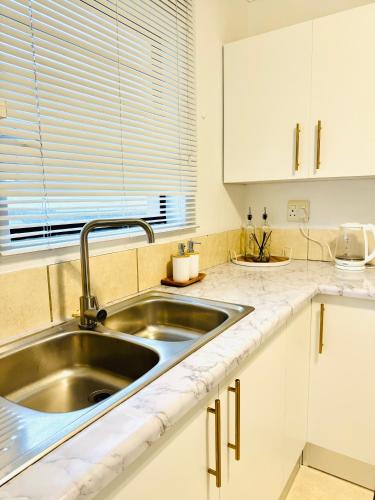 a kitchen with a sink and white cabinets at The Cherry Apartment Nahoon Valley in East London
