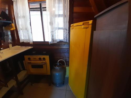 a small kitchen with a yellow refrigerator and a window at chalé alpino in Saquarema