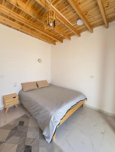 a bed in a white room with a wooden ceiling at Blue Villa in Lighthouse in Dahab