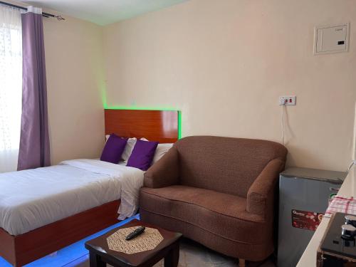 a small bedroom with a bed and a chair at Pearl Studio in Machakos
