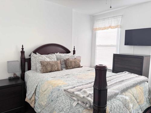 a bedroom with a large bed and a flat screen tv at Cozy spacious family home near Carytown fully fenced in Richmond