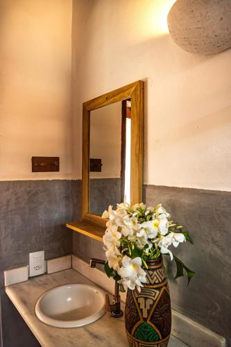 a vase with flowers on a counter in a bathroom at La hospedaria in Trancoso