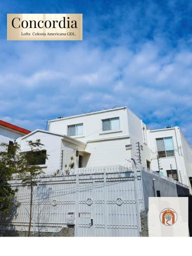 a white building with a fence in front of it at Concordia Lofts colonia americana Guadalajara in Guadalajara