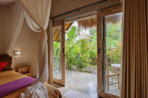 a bedroom with a bed and a large window at Cassava Penida Cottage in Nusa Penida