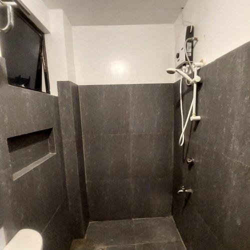 a bathroom with a shower with a black tile wall at Kalachuchi Place by Aman Sinaya in General Luna