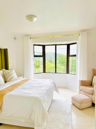 a white bedroom with a large bed and a window at The Cherry Apartment Nahoon Valley in East London