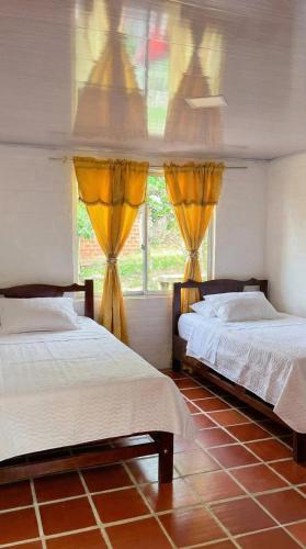 two beds in a room with a window at Casa sendai2 in Buesaco