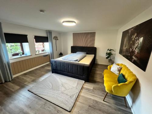a bedroom with a bed and a yellow chair at Suite 2 SZ- Lichtenberg in Salzgitter