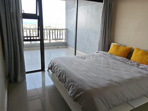 a bedroom with a bed with yellow pillows and a balcony at Vene's Place in Mossel Bay
