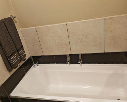 a white bath tub in a bathroom with tiles at Vene's Place in Mossel Bay