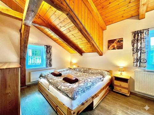 a bedroom with a large bed in a room with wooden ceilings at Apartmán Jizerské údolí in Kořenov