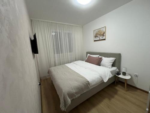 ein kleines Schlafzimmer mit einem Bett und einem Fenster in der Unterkunft Gold Star Apartman in Ruma