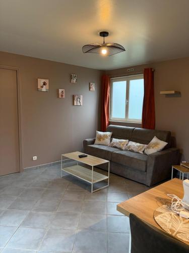 a living room with a couch and a table at Jardin des prés in Le Thil-en-Vexin