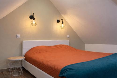 a bedroom with an orange bed and two lights at COCON Mayennais - Loft Balnéo Laval in Laval