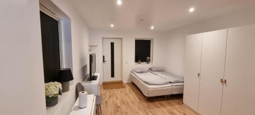 a white bedroom with a bed and a television at Apartment in Skogås in Skogås
