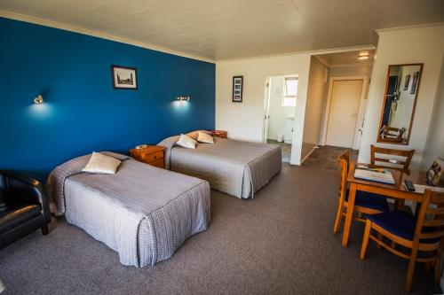 a bedroom with two beds and a blue wall at AAA Thames Court Motel in Oamaru