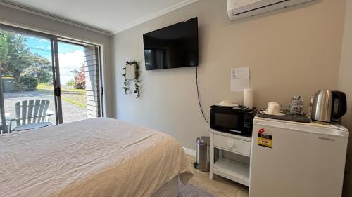 a bedroom with a bed and a tv on the wall at Peace and quiet on the beautiful North Shore in Auckland