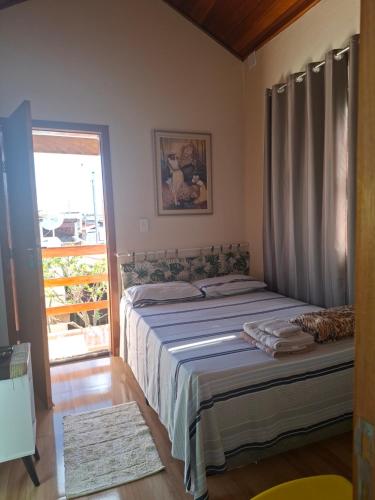 a bedroom with a bed and a window and a door at Suítes da Rô - hospedaria familiar diária e temporada in Varginha