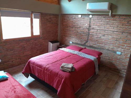a bedroom with a red bed and a brick wall at Cabaña Cholito in Lago Puelo