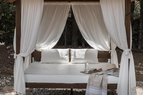 a bed with white curtains and a table at Finca Es Torrent in Campos