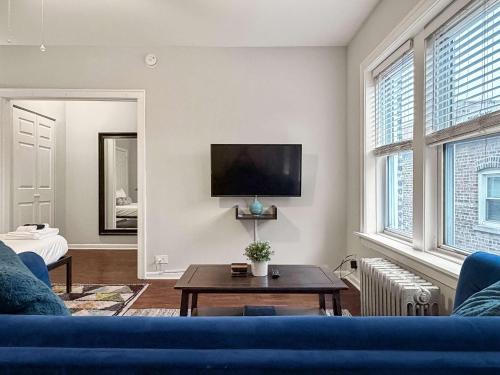 a living room with a blue couch and a tv at Sunlit Studio with City Charm - Lunt studio rep in Chicago