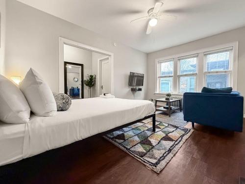 a bedroom with a white bed and a blue chair at Sunlit Studio with City Charm - Lunt studio rep in Chicago