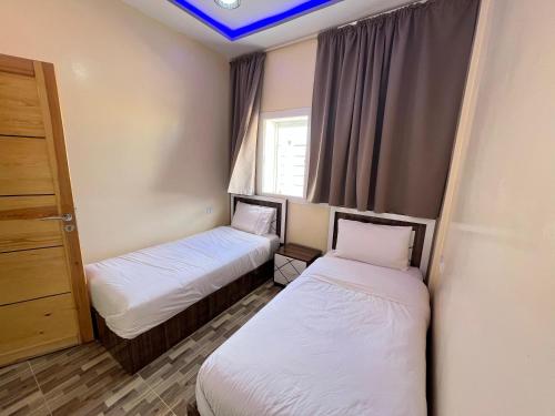 two beds in a small room with a window at Residence Almahaj in Laayoune