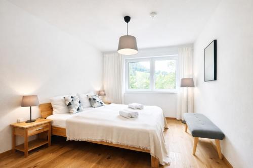 ein weißes Schlafzimmer mit einem Bett und einem Fenster in der Unterkunft Apartment Frida by Da Alois in Gröbming
