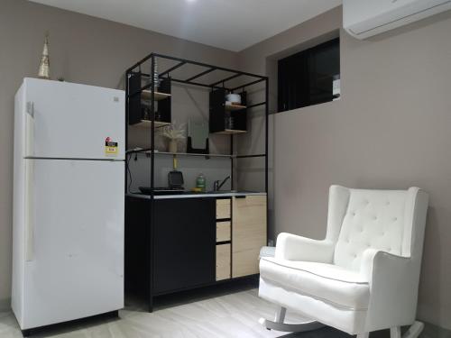 a living room with a white chair and a refrigerator at The Cosy Beach Nook 2BR Near Airport & Beach in Sydney