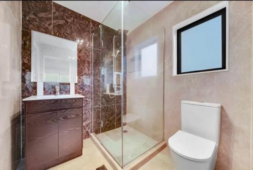 a bathroom with a toilet and a glass shower at Unique homestay in Auckland