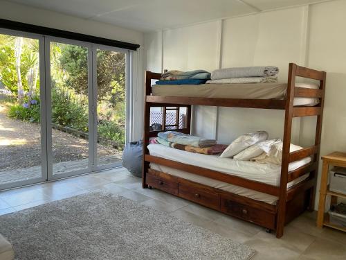 a room with two bunk beds and a sliding glass door at Blue Horizon Hideaway in Matapouri