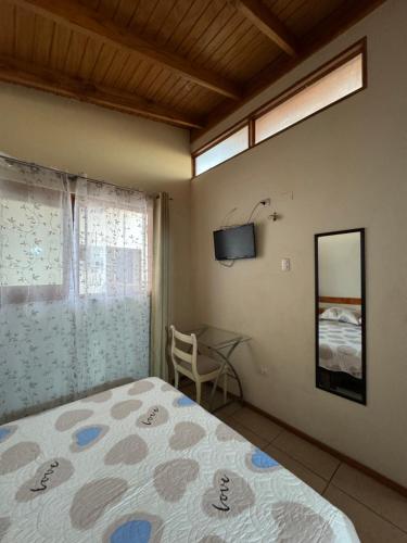 a bedroom with a bed and a table and a television at Hostal Asuncion in Arica