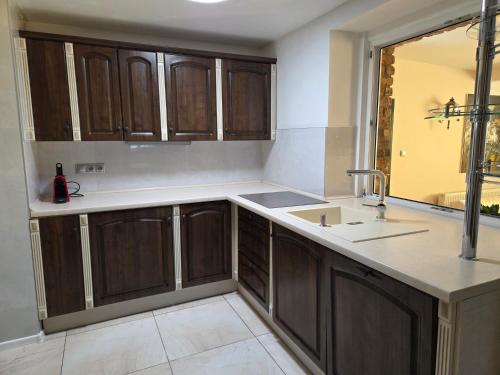 an empty kitchen with wooden cabinets and a sink at R Limoli Cozy in Trávnica