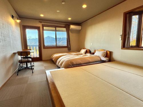 a bedroom with two beds and a desk and windows at Place yatsugatake Lodge&cottage in Hokuto