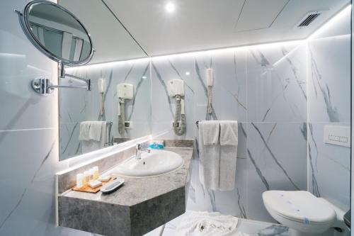 a bathroom with a sink and a toilet and a mirror at فندق نايل ستوري سوهاج in Sūhāj