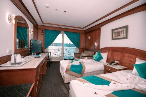 a train room with two beds and a television at فندق نايل ستوري سوهاج in Sūhāj