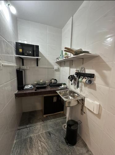 a small kitchen with a sink and a microwave at Diamond Ridge Living 1RK G-02 in Haidar Sāhibgūda