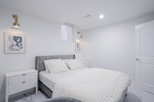 a white bedroom with a bed and a nightstand at Bright Modern 1BR Suite Free Parking Fast WiFi Self Check-In in Bowmanville