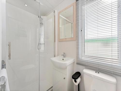 a white bathroom with a toilet and a sink at Comfortable mobile home in Middelkerke in Middelkerke