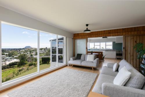 a living room with two couches and a large window at The Hilltop Hideaway in Tauranga