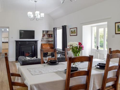 a dining room with a table with chairs and a fireplace at Tyn Y Coed in Bettws-Evan