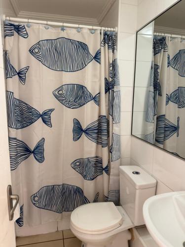 a bathroom with a shower curtain with fish on it at Departamento frente a la playa in Arica