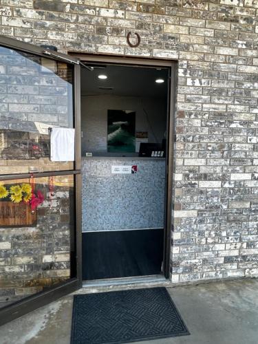 an open door to a brick walled room with a door at Coachman's Inn & Suites in Waldron