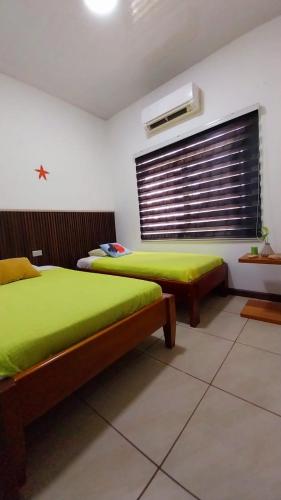 a bedroom with two beds with green sheets and a window at Genovesa Family home in Puerto Ayora