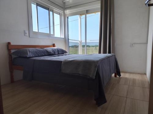 a bedroom with a bed with a large window at Beach house - Praia Recreio Torres in Torres